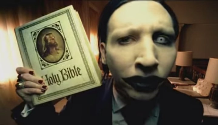Marilyn Manson, qui con la Bibbia (il libro dei libri) in una scena del video di "Beat the Devil". Sta per arrivare il suo nuovo disco, "THE PALE EMPEROR"