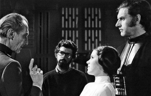 Peter Cushing, David Prowse e Carrie Fisher insieme al regista George Lucas sul set del primo film della daga di Star Wars, ‘Una Nuova Speranza’