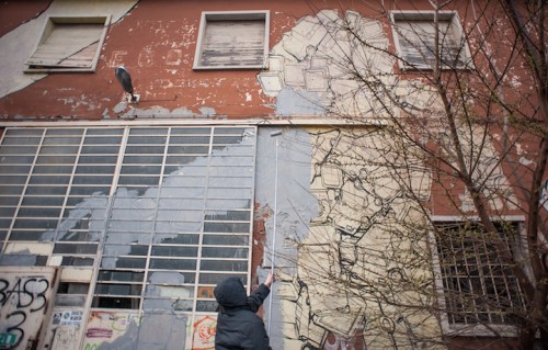 Blu mentre cancella i suoi graffiti a Bologna. Foto: Giap