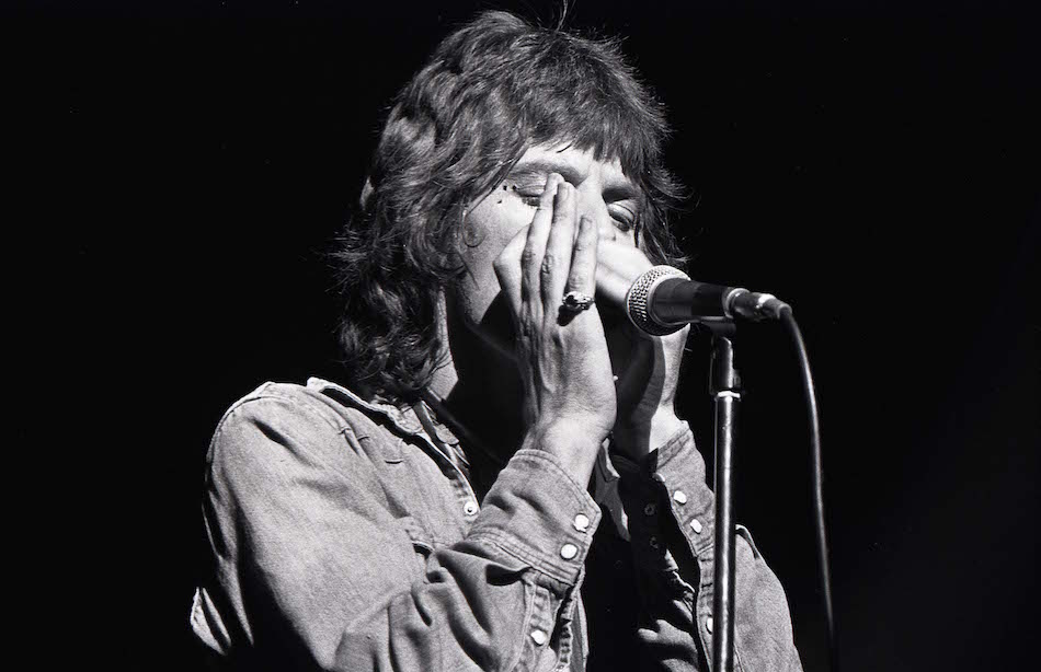 Mick suona l'armonica durante una performance negli anni '70 (Photo by Robert Knight Archive/Redferns)